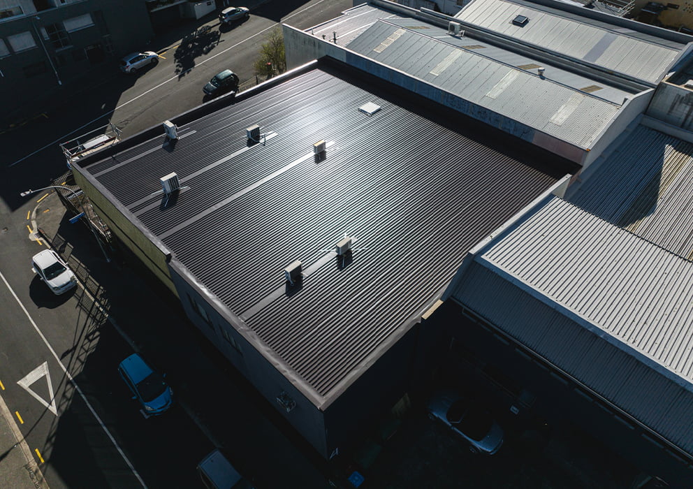 Aerial image of a commercial building with new black long run roofing.