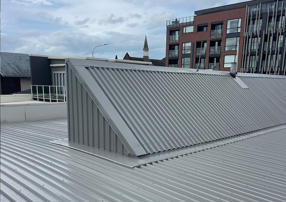 Image showing contours of a new grey long run roof on a commercial building.