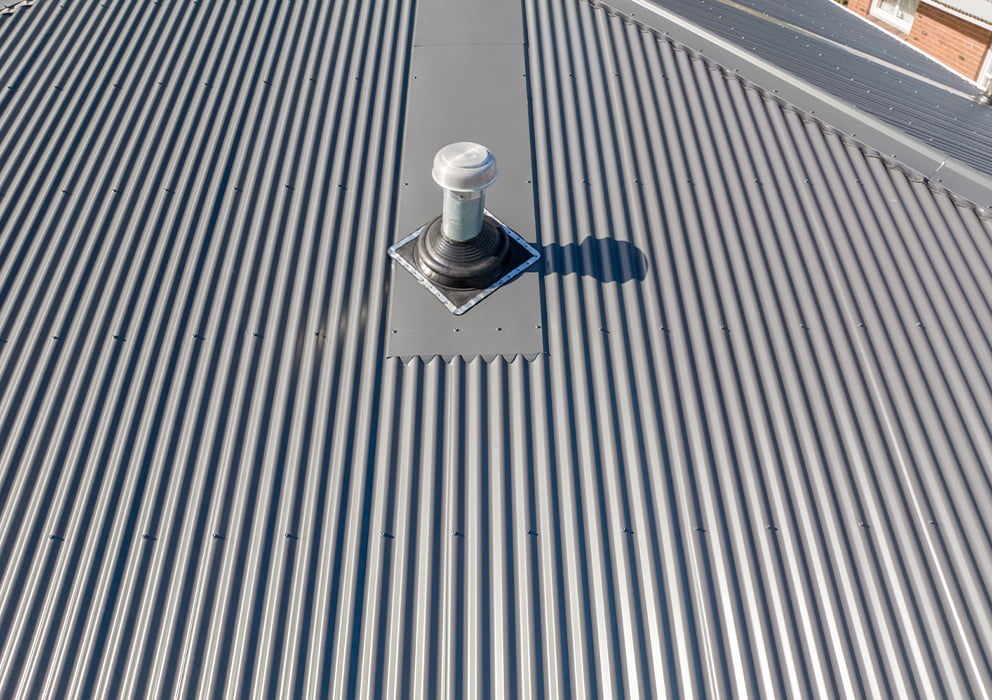 Close up of a chimney vent on a new grey long run roof.