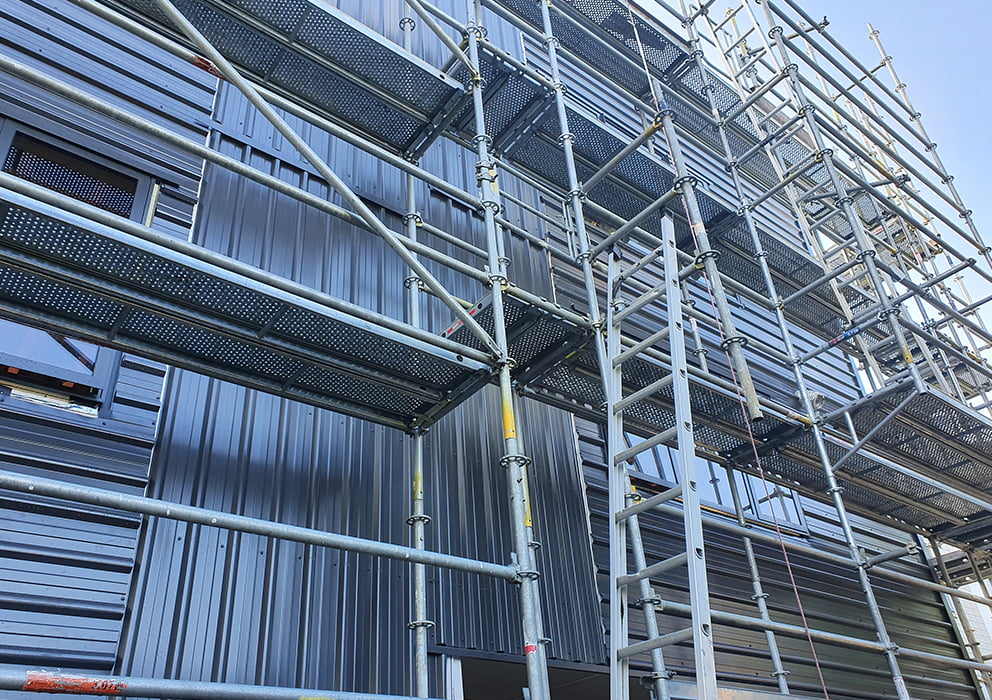 Scaffolding surrounding a new build with steel cladding.