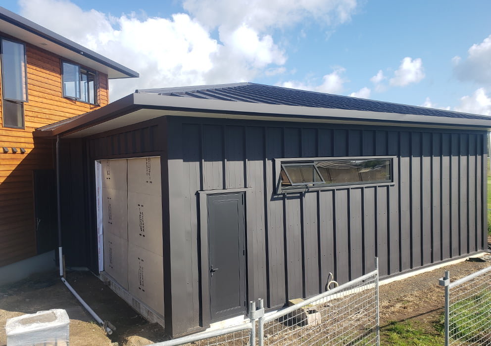 A new build house with black steel cladding and long run roofing.